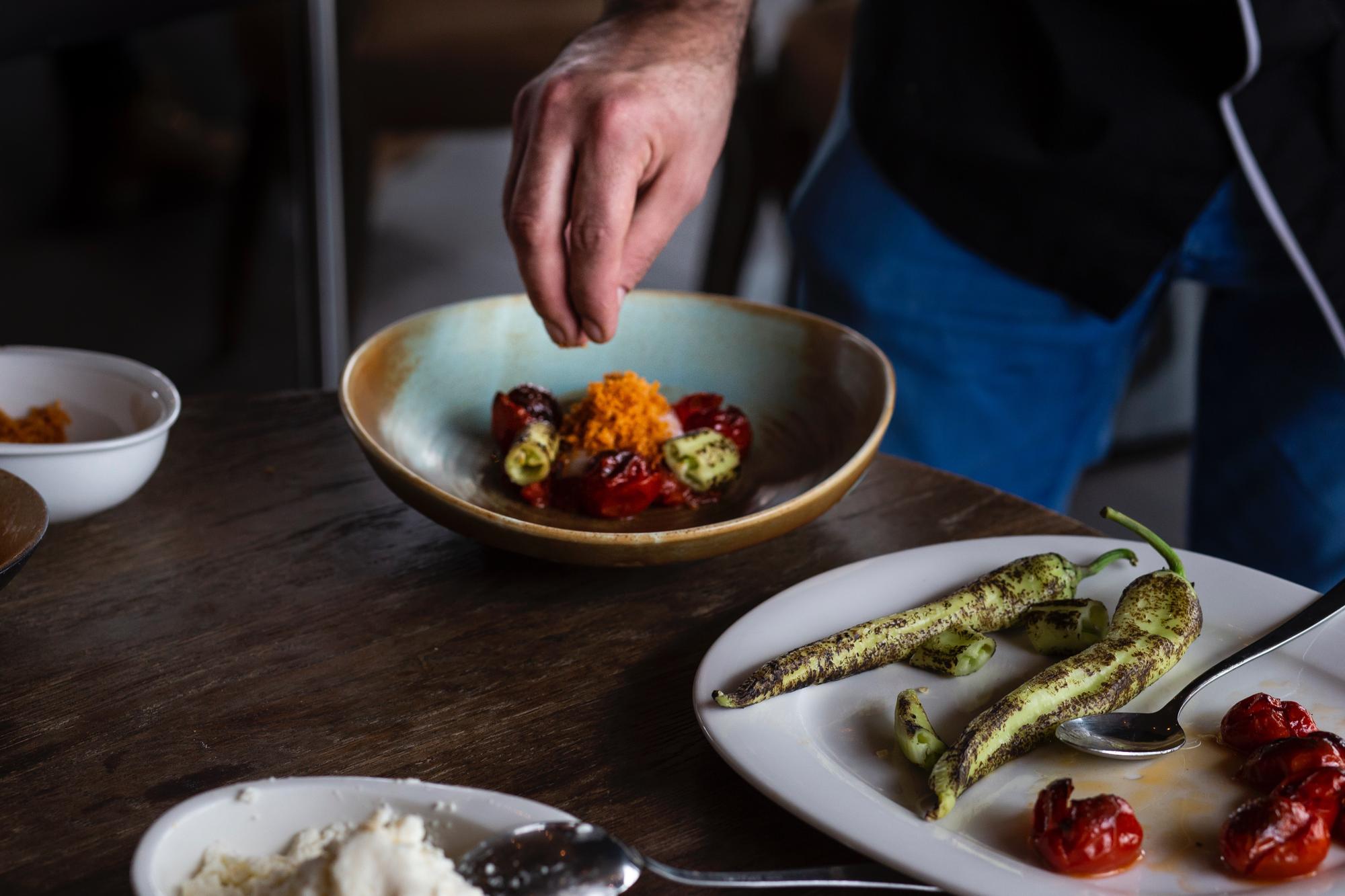 Chef plating modern dish on a quiet wooden table